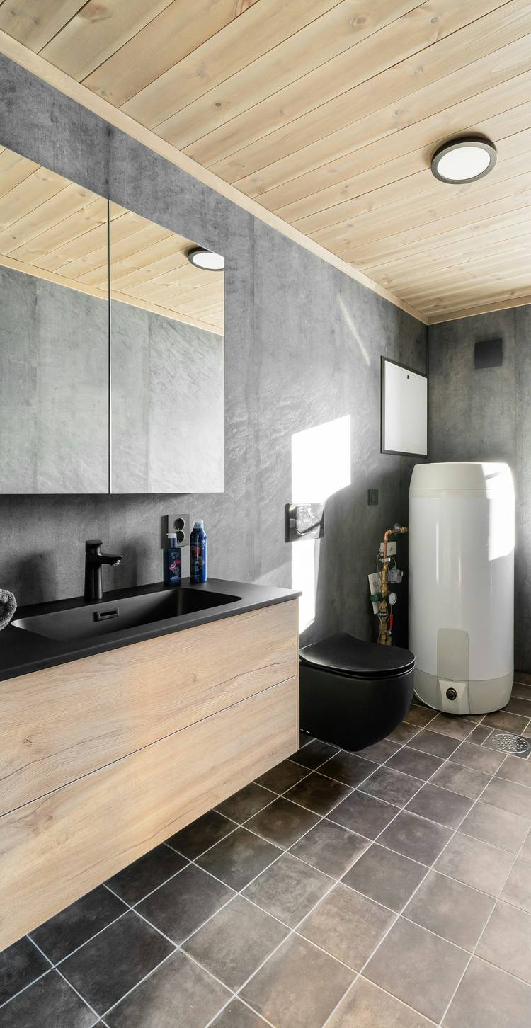 Vertical hot-water cylinder with its valve set, beside a bathroom vanity