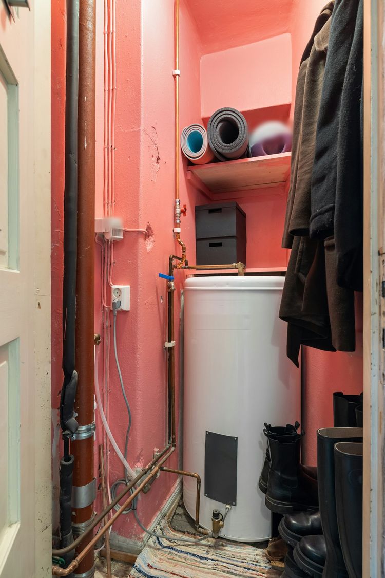 Electric hot-water cylinder in a cupboard with copper pipework and an isolating valve
