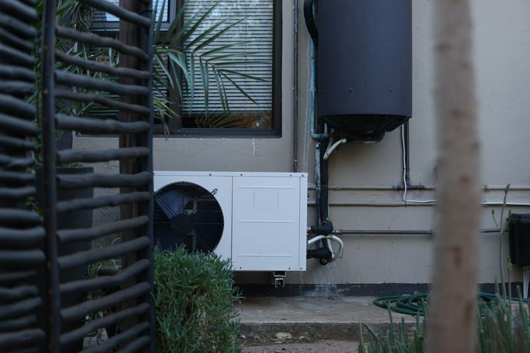 Hot-water cylinder and heat pump unit mounted on an outside wall