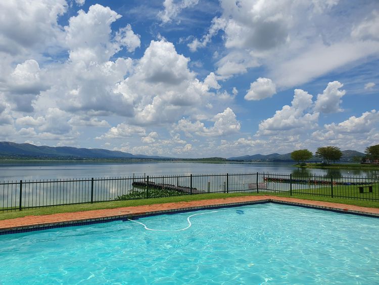 Swimming pool with paved coping and a lake and hills beyond
